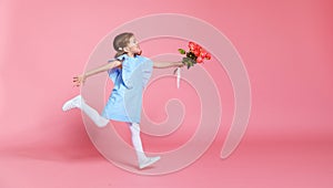 Funny child girl runs and jumps with bouquet of flowers on color