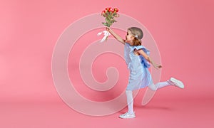 Funny child girl runs and jumps with bouquet of flowers on color