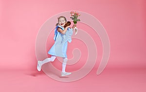 Funny child girl runs and jumps with bouquet of flowers on color