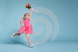 Funny child girl runs and jumps with bouquet of flowers on color