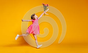 Funny child girl runs and jumps with bouquet of flowers on color