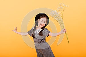 Funny child girl smiling with bouquet of flowers on a coloured background