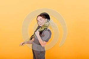 Funny child girl smiling with bouquet of flowers on a coloured background