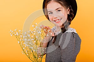 Funny child girl smiling with bouquet of flowers on a coloured background