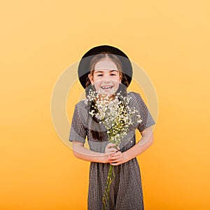 Funny child girl smiling with bouquet of flowers on a coloured background