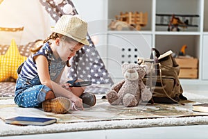 Funny child girl tourist with world map, backpack and magnifier