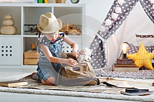 Funny child girl tourist with world map, backpack and magnifier