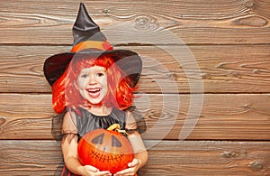 Funny child girl in witch costume for Halloween with pumpkin Ja