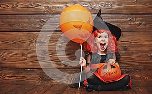 Funny child girl in witch costume for Halloween with pumpkin Ja