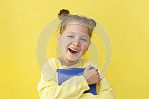 Funny child girl yellow jacket on a yellow background, sitting, reading a book, development and school concept