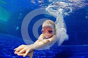 Funny child in goggles dive in swimming pool