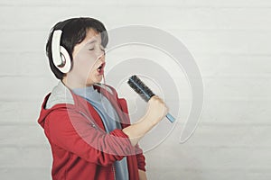 Funny child in headphones singing with hair brush