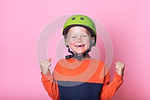Funny child in helmet with hands up. Happy kid having fun outdoor. Kid dreams and imagin big. Portrait of proud blond photo