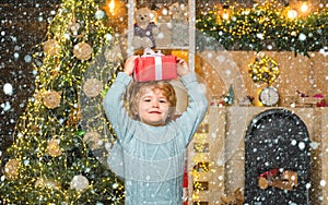 Funny child holding a red gift box with both hands. Christmas Celebration holiday. Happy little child dressed in winter