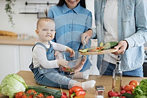 Funny child making angry face while holding bowl for salad