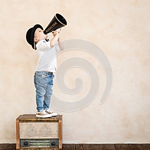 Funny child playing with black retro megaphone