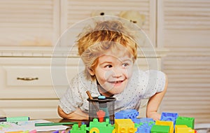 Funny child plays in the constructor in playroom, kids funny face. Kids playing with colorful blocks, head portrait.