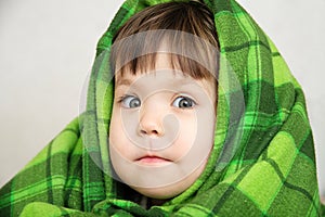 Funny child portrait in blanket warming, happy smiling kid face expressing emotion, little girl looking at camera, warm blanket