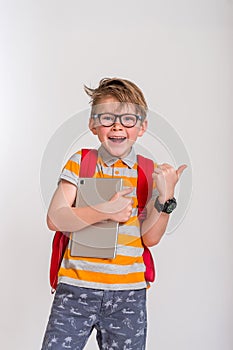 Funny child portrait, shocked, surprised, funny looking boy with glasses using, holding laptop, pad computer. Human face