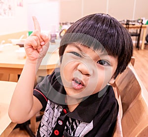 Funny child posing angry waiting for food in restaurant.