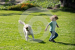 Funny child run with dog. Happy kid boy playing with dog in garden. Child runnin with a dog in park.