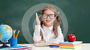 Funny child   schoolgirl    student  raises his hand up near school blackboard