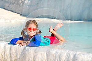 Funny child in swimming clothes relax in hot pool. Smiling cute little girl in sunglasses in pool in sunny day. Child in