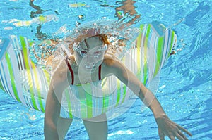 Funny child swims in pool under water, kid having fun and playing with rubber ring, little girl on vacation