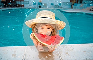 Funny child with watermelon. Kid having fun in swimming pool. Summer vacation and healthy eating.