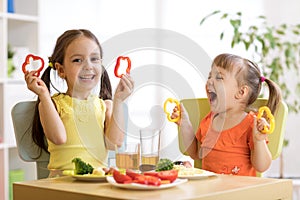 Funny children girls eating healthy food. Kids lunch at home or kindergarten.