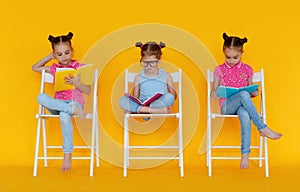 Funny children girls read books on colored yellow background