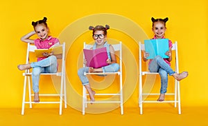 Funny children girls read books on a colored yellow background