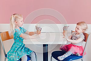 Funny children girls sitting together bragging boasting their ice-cream photo