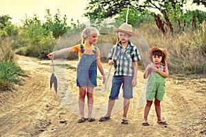 Funny children go fishing in the summer evening on a dirt road