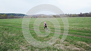 Funny children run around the green field in the spring.