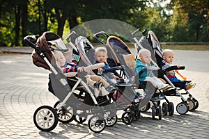 Funny children sitting in strollers in park