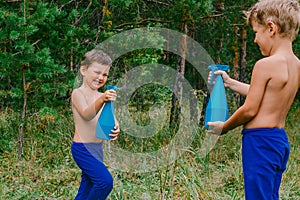 Funny children splash water in the summer in the forest photo