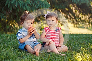 Funny children toddlers sitting together sharing apple food