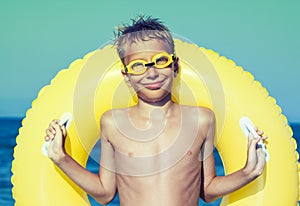 Funny chilld with swimmer goggles standing on beach photo