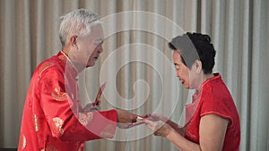 Funny Chinese elder husband giving lot of red envelop to wife for Chiense New Year
