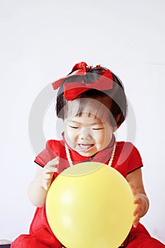 Funny Chinese little baby in red cheongsam play yellow balloon