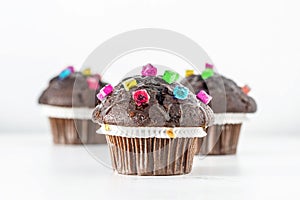 Funny Chocolate Muffins decorated with colorful candies on white background