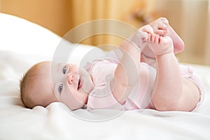 Funny chubby baby infant girl playing with her feet