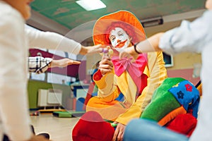 Funny clown gives out lollipops to happy children