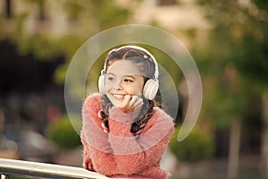 Funny cool stylish girl is listening to music and thinking about positiveness. Girl standing on the bridge with