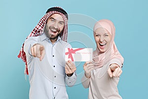 Funny couple friends arabian muslim man wonam in keffiyeh kafiya ring igal agal hijab clothes isolated on blue photo