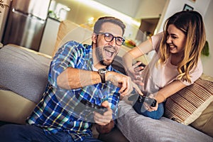 Funny couple playing video games at home