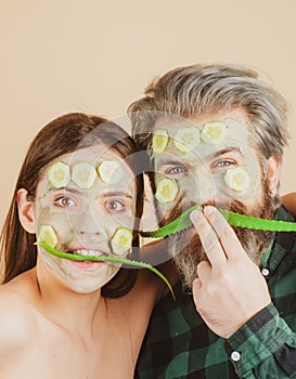 Funny couple spa mask, aloe vera and cucumber on face. Mud facial mask, face clay mask spa. Man and woman with cosmetic