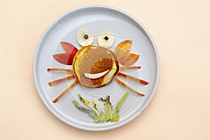 Funny crab face shape snack from pancake,apples,banana,kiwi on plate. Cute kids childrens baby`s sweet dessert, healthy breakfast
