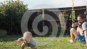 Funny Crawling Baby Toddler Boy On Backyard Lawn Grass. Baby and Dad in the Garden Summer Time. Family Time enjoing